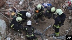 Emergency workers retrieve the body of a 10-year old boy who was killed in a Russian air attack that hit a multistory building in central Kharkiv, Ukraine, Oct. 6, 2023.