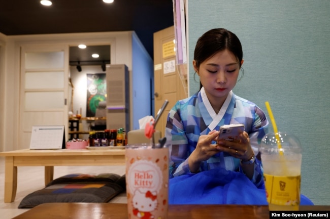 Lee Kyoung-hyun, a popular YouTuber shaman, looks at her phone at her shaman parlor in Seoul, May 13, 2024. (REUTERS/Kim Soo-hyeon)