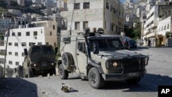 A convoy of Israeli military vehicles drives through the West Bank city of Nablus, during a raid, May 4, 2023.