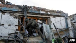 A military investigator gets out of the window of a house hit by shelling, that killed a man and injured a woman, in Donetsk, Russian-controlled Ukraine, Oct. 24, 2023.