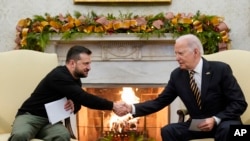 Presiden Joe Biden berjabat tangan dengan Presiden Ukraina Volodymyr Zelenskyy saat mereka bertemu di Ruang Oval Gedung Putih, Washington, D.C., Selasa, 12 Desember 2023. (AP/Evan Vucci)