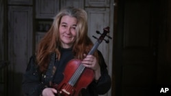 Oksana, 49, who did not want her surname reported, shows a violin she made herself in her small and cold apartment in Bakovka, on the outskirts of Moscow, Russia, Tuesday, Feb. 8, 2022.