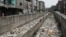 People walk along a street next to a sewage canal filled with garbage at Seelampur neighborhood in New Delhi, April 26, 2023.