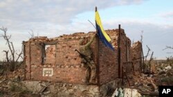 FILE - A Ukrainian serviceman raises the Ukrainian flag as a symbol of liberation in the front-line village of Andriivka, Donetsk region, Ukraine, Sept. 16, 2023.
