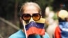 ARCHIVO - Una mujer sujeta la bandera de Venezuela sobre parte de su rostro. En Caracas, marzo de 2020. 