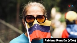 ARCHIVO - Una mujer sujeta la bandera de Venezuela sobre parte de su rostro. En Caracas, marzo de 2020. 