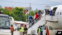 FILE - Haitians deported from the United States deplane at the Toussaint Louverture International Airport in Port au Prince, Haiti, Sept. 19, 2021.