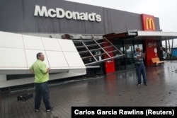 Para pekerja berdiri di luar restoran McDonald's yang rusak setelah Topan Koinu melewati ujung selatan Taiwan, di KentingTaiwan 5 Oktober 2023. (Foto: REUTERS/Carlos Garcia Rawlins)