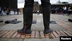 ARCHIVO - Un hombre usa botas de goma con pintura roja que representa sangre, durante una protesta simbólica, en Bogotá, Colombia, el 30 de agosto de 2021.