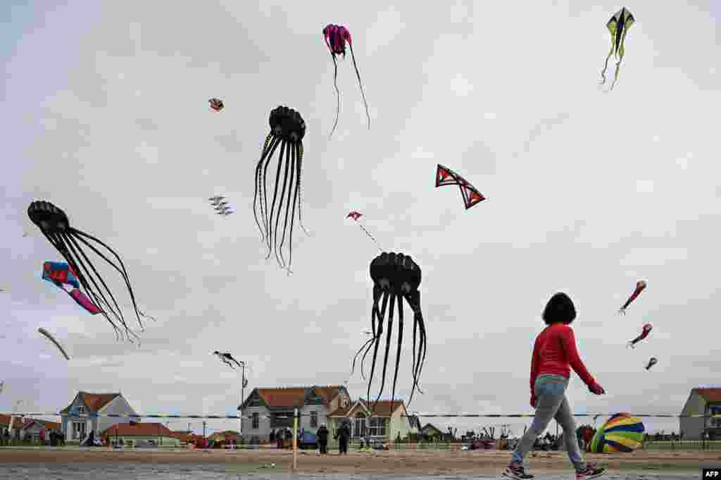 A woman walks past flying kites during the 29th edition of the International Kite and Wind Festival in Chatelaillon-Plage, south-western France, April 10, 2023.