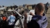 FILE - United Nations staff members inspect the carcass of a car used by US-based aid group World Central Kitchen, that was hit by an Israeli strike the previous day in Deir al-Balah in the central Gaza Strip on April 2, 2024,