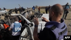 FILE - United Nations staff members inspect the carcass of a car used by US-based aid group World Central Kitchen, that was hit by an Israeli strike the previous day in Deir al-Balah in the central Gaza Strip on April 2, 2024,