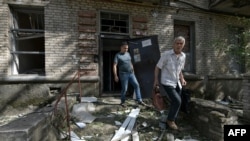 Local residents leave a destroyed residential building after a missile attack in Lugansk, Russian-controlled Ukraine, June 7, 2024.