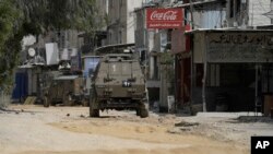 Israeli military vehicles drive during an operation in the nearby Nur Shams refugee camp, near the West Bank town of Tulkarm, April 20, 2024.