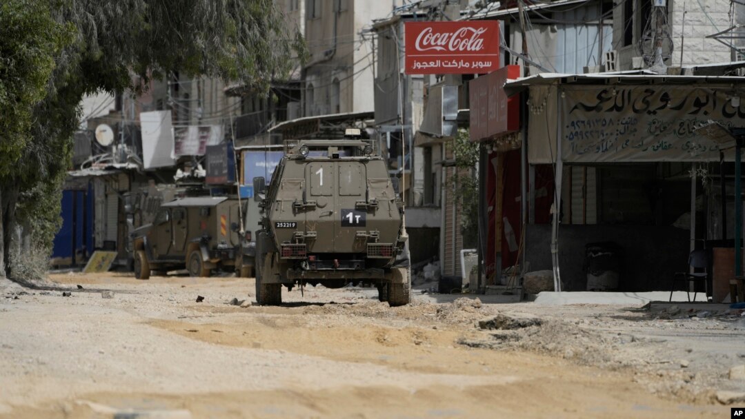 FILE - Israeli military vehicles drive during an operation in the nearby Nur Shams refugee camp, near the West Bank town of Tulkarm, April 20, 2024.