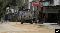FILE - Israeli military vehicles drive during an operation in the nearby Nur Shams refugee camp, near the West Bank town of Tulkarm, April 20, 2024.
