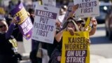 Martha Canul, foreground, a medical assistant at Kaiser, holds up signs along with medical workers and supporters as they protest outside of a Kaiser Permanente facility in San Francisco, Oct. 4, 2023.
