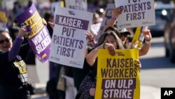 Martha Canul, foreground, a medical assistant at Kaiser, holds up signs along with medical workers and supporters as they protest outside of a Kaiser Permanente facility in San Francisco, Oct. 4, 2023.