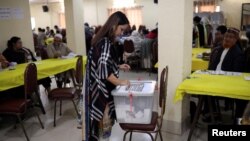 বাংলাদেশের ঢাকায় সাধারণ নির্বাচনে ভোট দিয়ে একজন ভোটার তার ব্যালট পেপার বাক্সে ভরছেন। ৩০ ডিসেম্বর, ২০১৮ (ফাইল ছবি) 