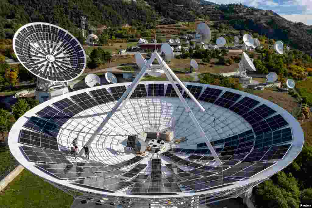 Employees of Swiss electricity producer and supplier CKW, part of Axpo, install solar panels in a satellite dish at the Leuk Teleport and Data Center in Leuk, Switzerland, Oct. 18, 2023. REUTERS/Denis Balibouse