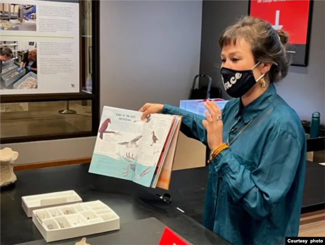 Jingmai O'Connor shows her book WHEN DINOSAURS CONQUERED THE SKIES, illustrated by Maria Brzozowska. (Photo from publisher The Quarto Group)