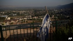 Una bandera israelí cuelga en un área con edificios como telón de fondo en Kiryat Shmona, una ciudad junto a la frontera con el Líbano, en el norte de Israel, el 19 de junio de 2024.