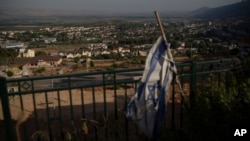 An Israeli flag hangs on an area backdropped by buildings in Kiryat Shmona, a city next to the border with Lebanon, northern Israel, June 19, 2024. 