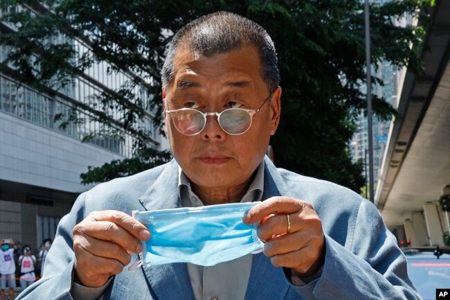 FILE - Hong Kong media tycoon Jimmy Lai, who founded the local newspaper Apple Daily, prepares to wear a face mask before entering a court in Hong Kong on May 5, 2020. (AP Photo/Kin Cheung, File)