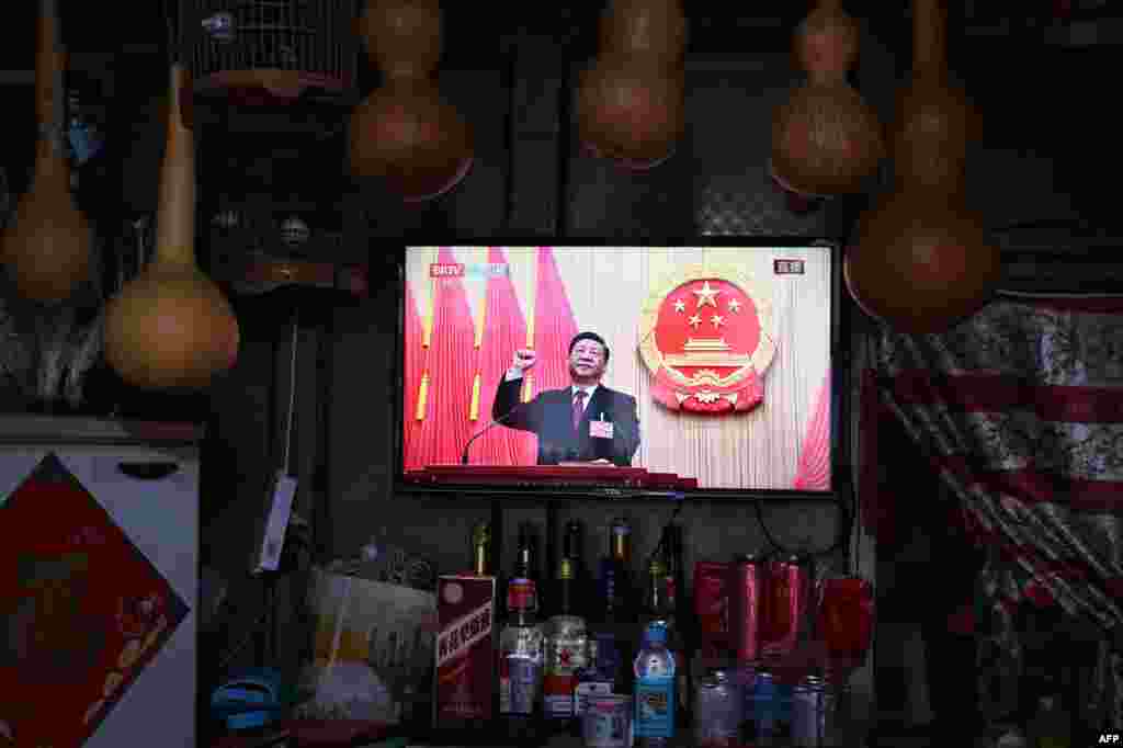 A TV screen at a store shows live coverage as Chinese President Xi Jinping swears an oath after being reelected as president for a third term during a of the National People&#39;s Congress in Beijing.