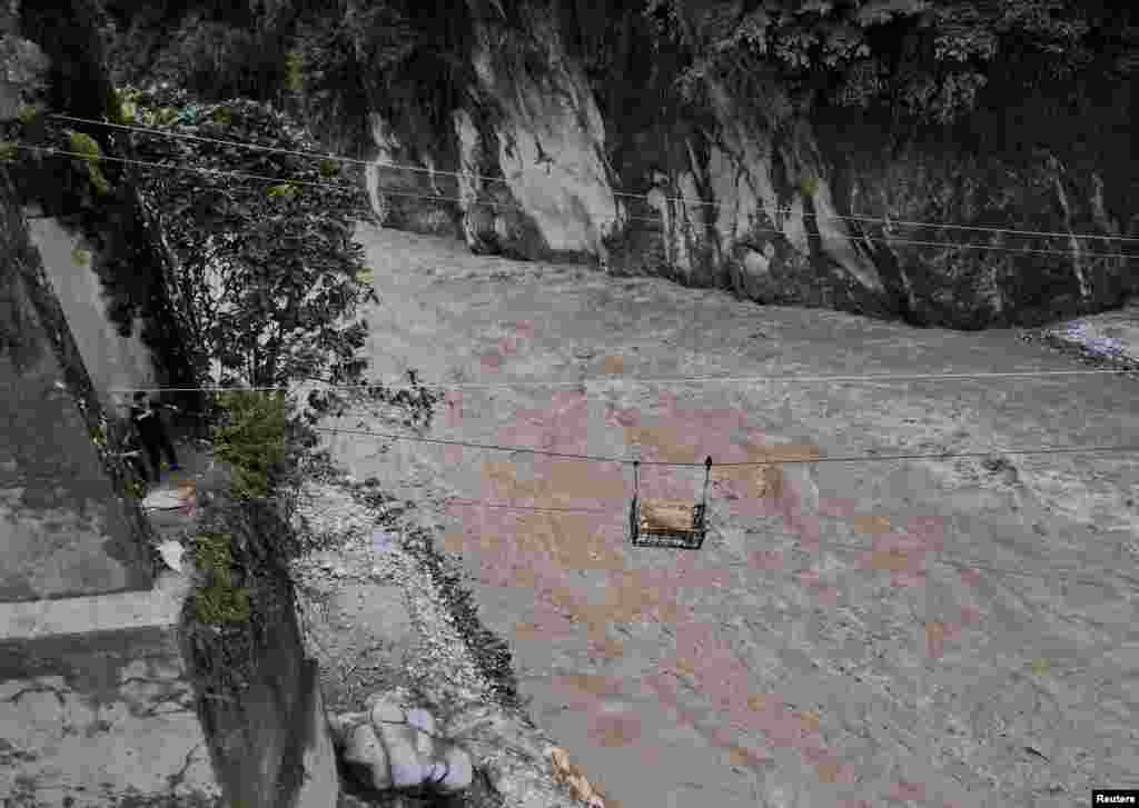 A basket carrying relief supplies is transported on a makeshift zip line across the Teesta river to Dzongu village,which became inaccessible after flash floods washed away a bridge at Sangkalang, Sikkim, India.