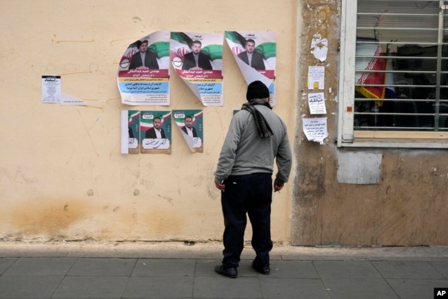 A man looks at electoral posters of candidates for the March 1 parliamentary election, in downtown Tehran, Iran, Feb. 22, 2024.