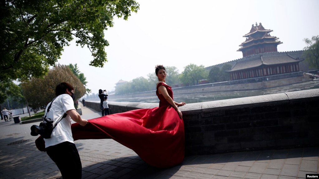一名摄影师在北京故宫角楼外为一名红衣女子拍摄婚纱照。（2020年5月1日）(photo:VOA)
