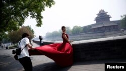 一名摄影师在北京故宫角楼外为一名红衣女子拍摄婚纱照。（2020年5月1日）