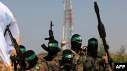 FILE - Palestinian fighters of the al-Qassam Brigades, the armed wing of the Hamas movement, take part in a military parade to mark the anniversary of the 2014 war with Israel, near the border in the central Gaza Strip on July 19, 2023. 