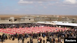 FILE - Coffins with remains of people from the Yazidi minoirty, who were killed by Islamic State militants, and they were exhumed from a mass grave, are seen during the funeral in Kojo, Iraq, Feb. 6, 2021.