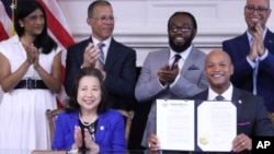 Maryland Gov. Wes Moore holds up an executive order he signed to issue more than 175,000 pardons for marijuana convictions in Annapolis, Maryland, June 17, 2024. 