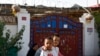 FILE - Uyghur youths play outside their house, with Chinese lanterns and barbed wire visible, at Unity New Village in Hotan, China, Sept 20, 2018. Xinjiang authorities have been replacing names of ethnic minorities' villages to reflect Communist ideology.