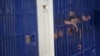 FILE - Detainees stand behind cell bars at the police Immigration Detention Center in central Bangkok on Jan. 21, 2019