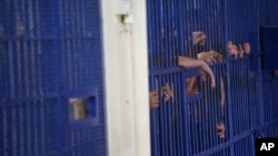 FILE - Detainees stand behind cell bars at the police Immigration Detention Center in central Bangkok on Jan. 21, 2019