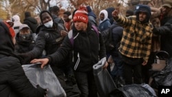 Migrants pick up blankets near a migrant assistance center at St. Brigid Elementary School on Dec. 5, 2023, in New York.