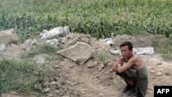 북한 주민이 나선시 외곽에 있는 자신의 밭 옆에 앉아있다. (자료화면)