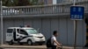 A man pushes a bicycle past by a police van stationed at a bridge along the Chang'an Avenue in Beijing, June 4, 2024. 