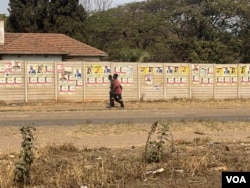 FILE - Zimbabweans walk past election posters of the country’s general election in Harare, Zimbabwe, Aug. 2023. (Columbus Mavhunga/VOA)