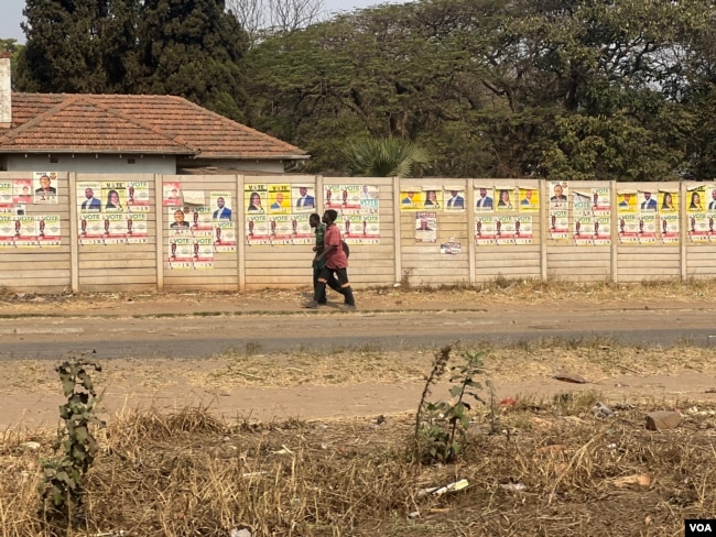 FILE - Zimbabweans walk past election posters of the country’s general election in Harare, Zimbabwe, Aug. 2023. (Columbus Mavhunga/VOA)