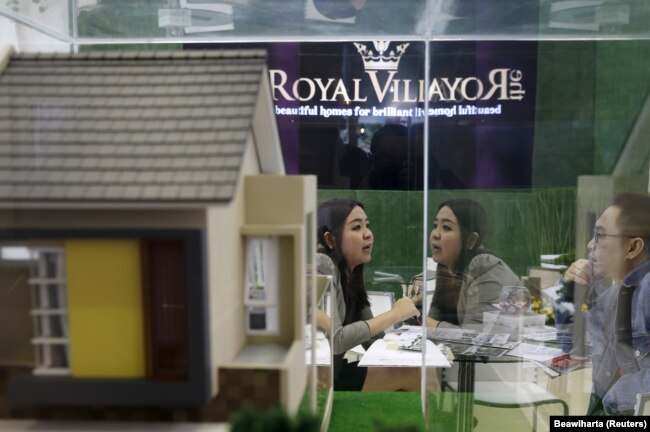 Seorang agen real estate (kiri) berbincang dengan pelanggannya di samping model properti saat Indonesia Property Expo 2016 di Jakarta, 16 Februari 2016. (Foto: REUTERS/Beawiharta)