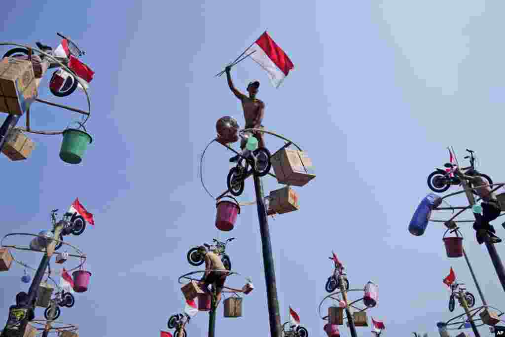 A participant celebrates after reaching the prizes during a greased-pole climbing competition held as a part of the Independence Day celebrations at Ancol Beach in Jakarta, Indonesia.