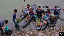 Environmental activist members of the Situ Gede Cleanliness Warrior pick up trash while paddling kayaks at Setu Gede lake in Bogor, West Java, Indonesia, Tuesday, Oct. 10, 2023. (AP Photo/Achmad Ibrahim)