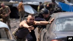 Emergency workers and soldiers push damaged cars after a Russian missile hit a supermarket in Kostiantynivka, Ukraine, Aug. 9, 2024.