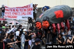 Para pengunjuk rasa membawa patung Presiden Filipina Ferdinand Marcos Jr dan mantan presiden Rodrigo Duterte dalam unjuk rasa memperingati 37 tahun revolusi "Kekuatan Rakyat", pada 25 Februari 2023. (Foto: AFP)