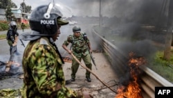 Maafisa wa polisi wa Kenya wakiondoa vizuizi kwenye barabara kuu huko Kibera jijini Nairobi tarehe 2 Mei, 2023. Picha na Luis Tato / AFP. 